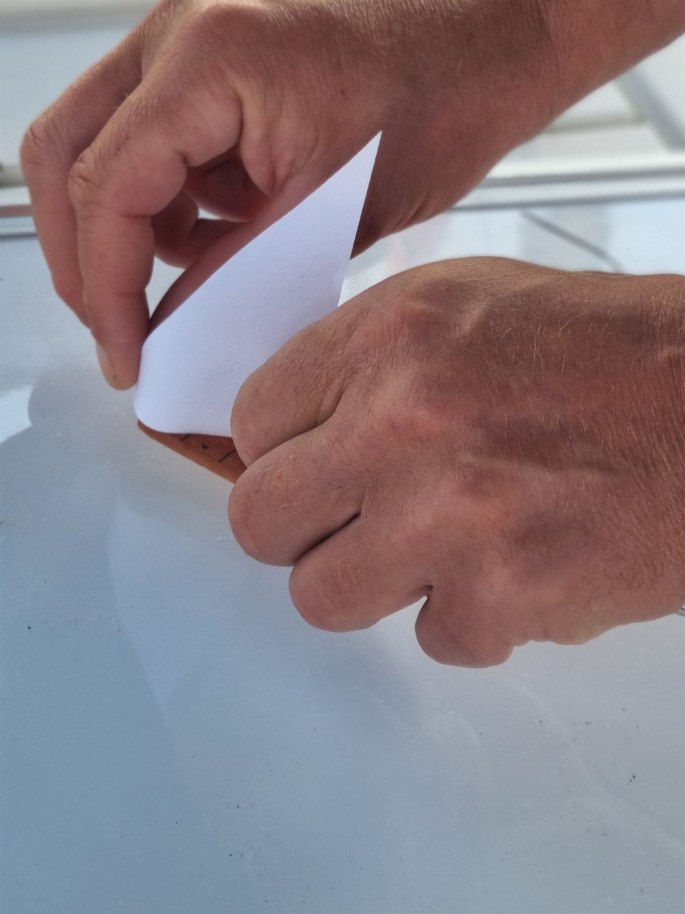 Close-up of hands folding paper on a whiteboard aboard a sailing yacht