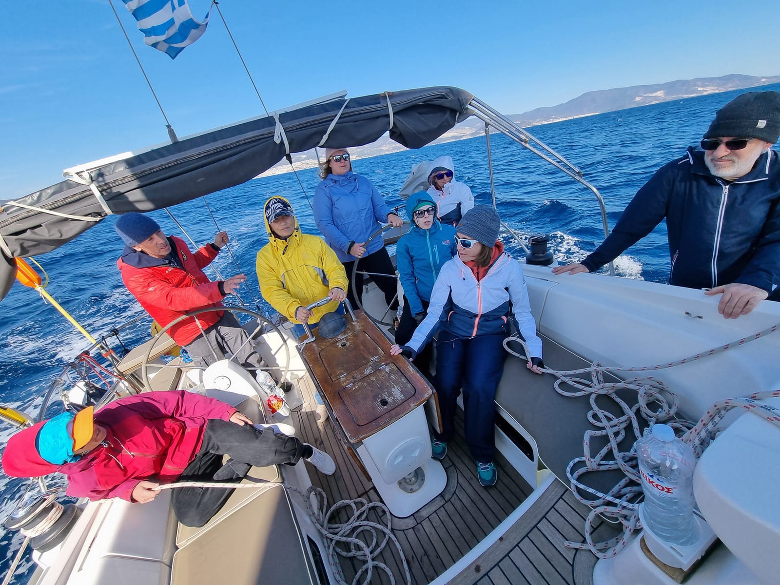 A full crew of participants working together aboard a sailing yacht